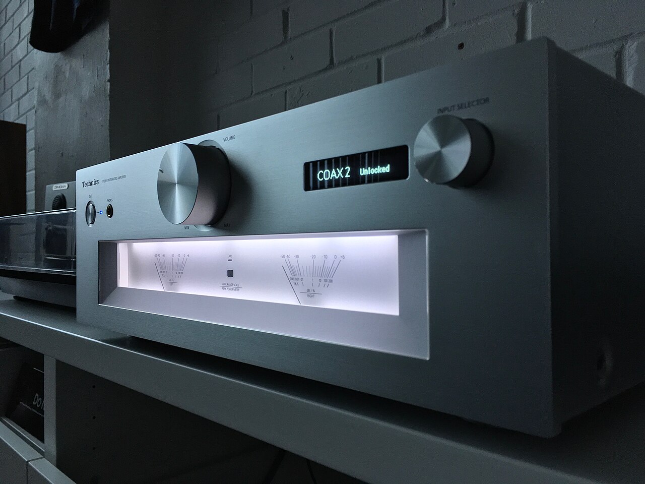 The illuminated output meters of an integrated stereo amplifier in a darkened room